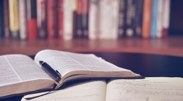 Open notebook with pen and bookshelf in background