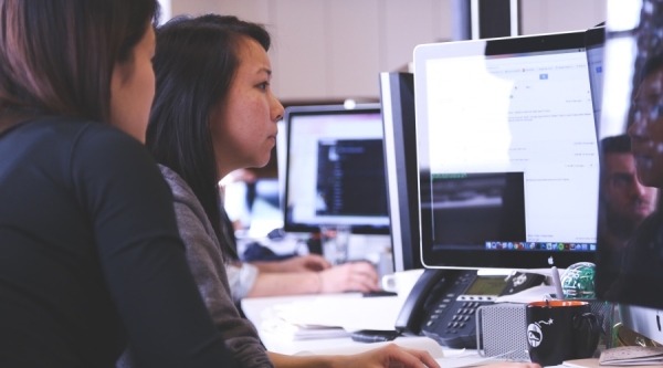 Two people sitting around a computer