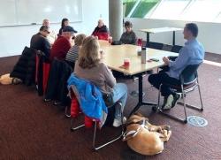 Group of people sitting around table with dog lying on the floor