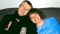 Young woman and an older woman sitting close together on a couch and smiling.