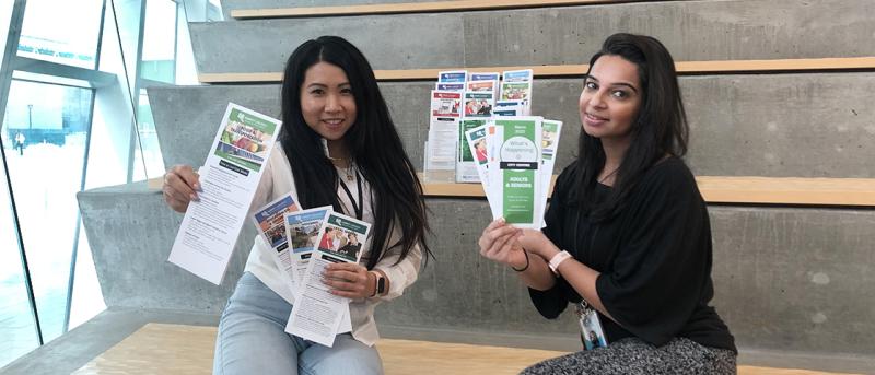 Two staff members holding brochures